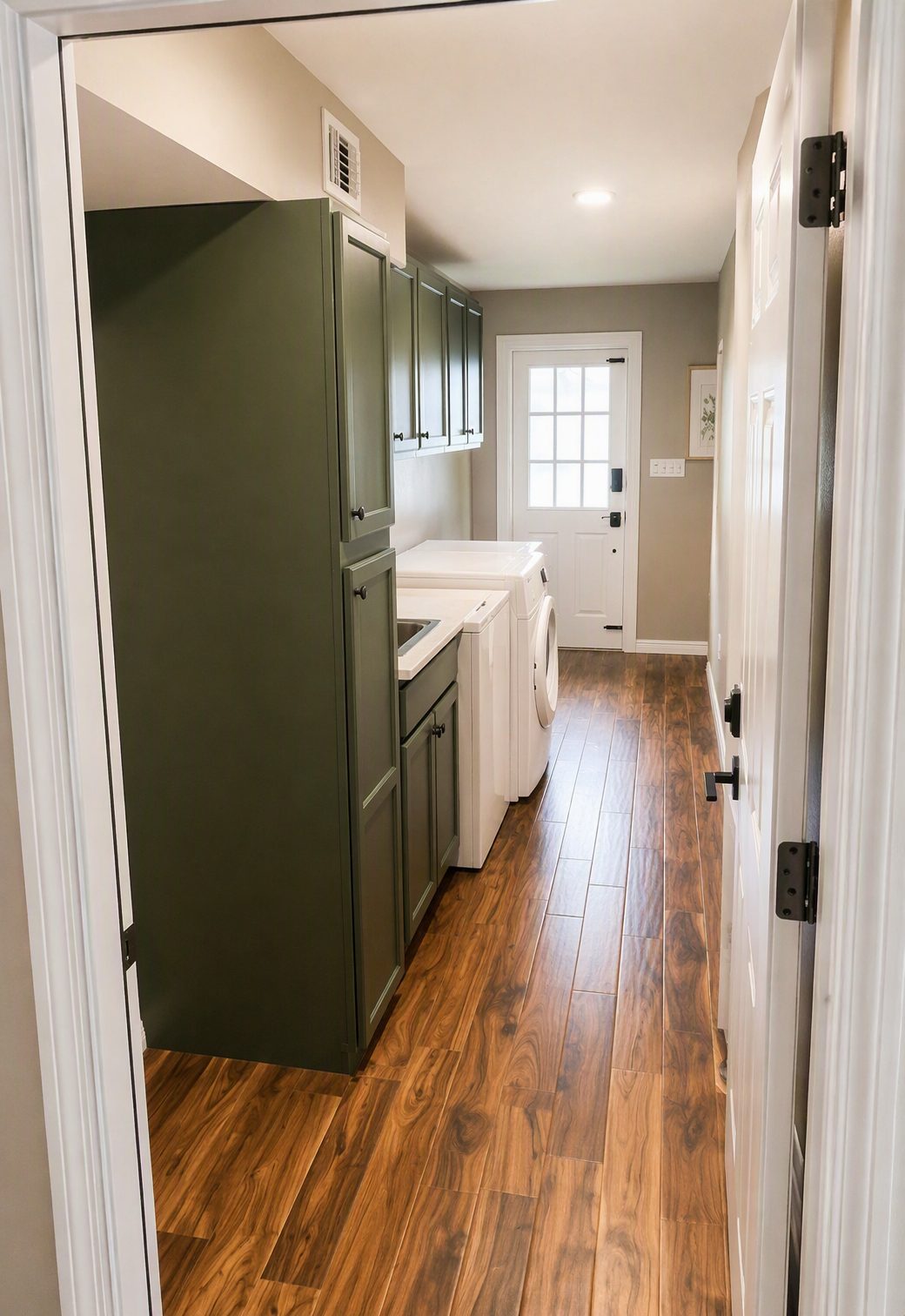 Laundry room after renovation by Wages Construction, with green cabinetry and wood-look flooring